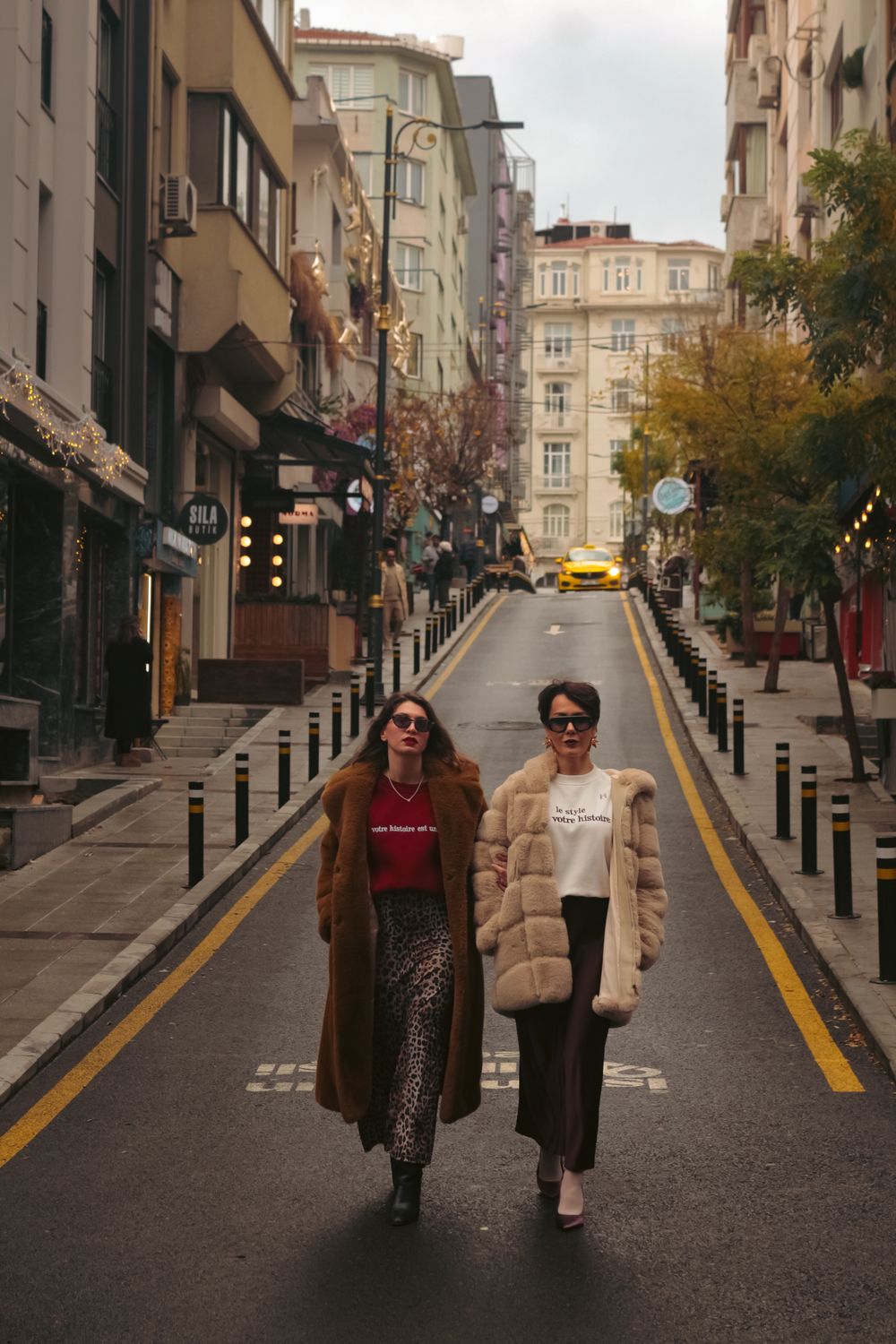 Two people in long coats walking through a city street